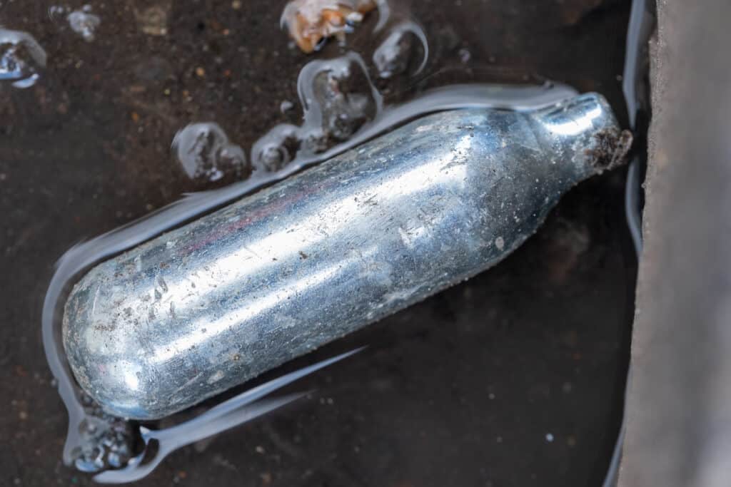 Nitrous oxide canister / cream charger found lying in the gutter: metal cylinder contained nitrous oxide gas, used for whipping cream, but also as a legal high.
