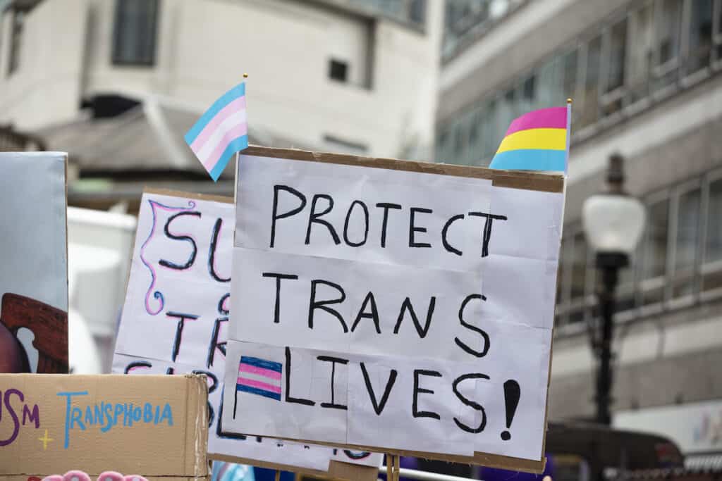 A person holding a sign reading protect trans lives banner