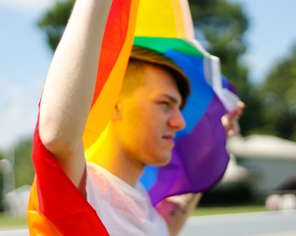 young male carrying rainbow flag