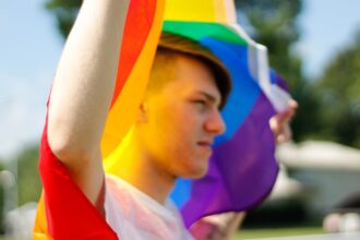 young male carrying rainbow flag