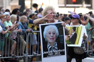 parade marcher carrying a poster in memory of Jeanne Manford