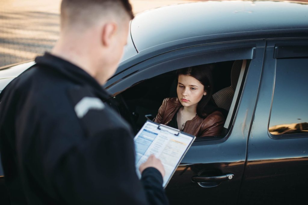 Policeman in uniform writes fine to young female driver