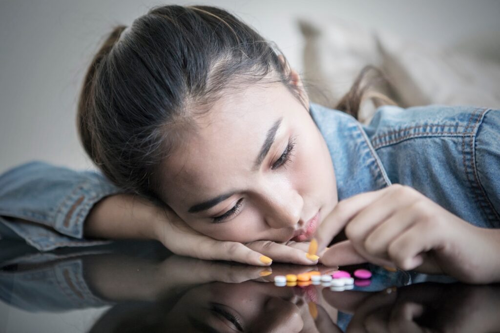 Close up of a teenage girl looks addicted while counting drugs on the table