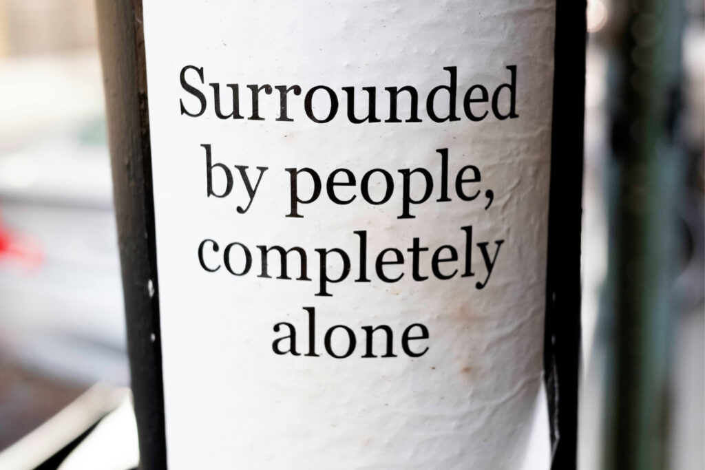 Sign on a street pole saying "Surrounded by people, completely alone"