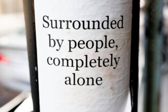 Sign on a street pole saying "Surrounded by people, completely alone"