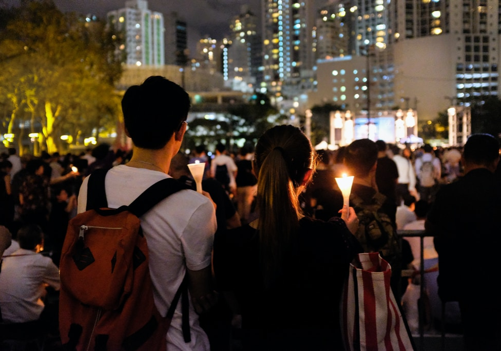 group of people holding candle near buildings