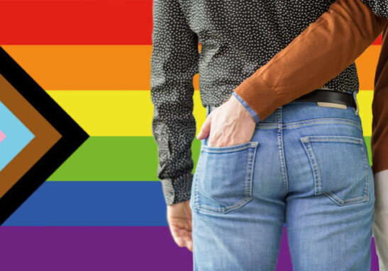 lgbtq, trans and intersex rights concept - close up of male gay couple hugging over progress pride flag on background